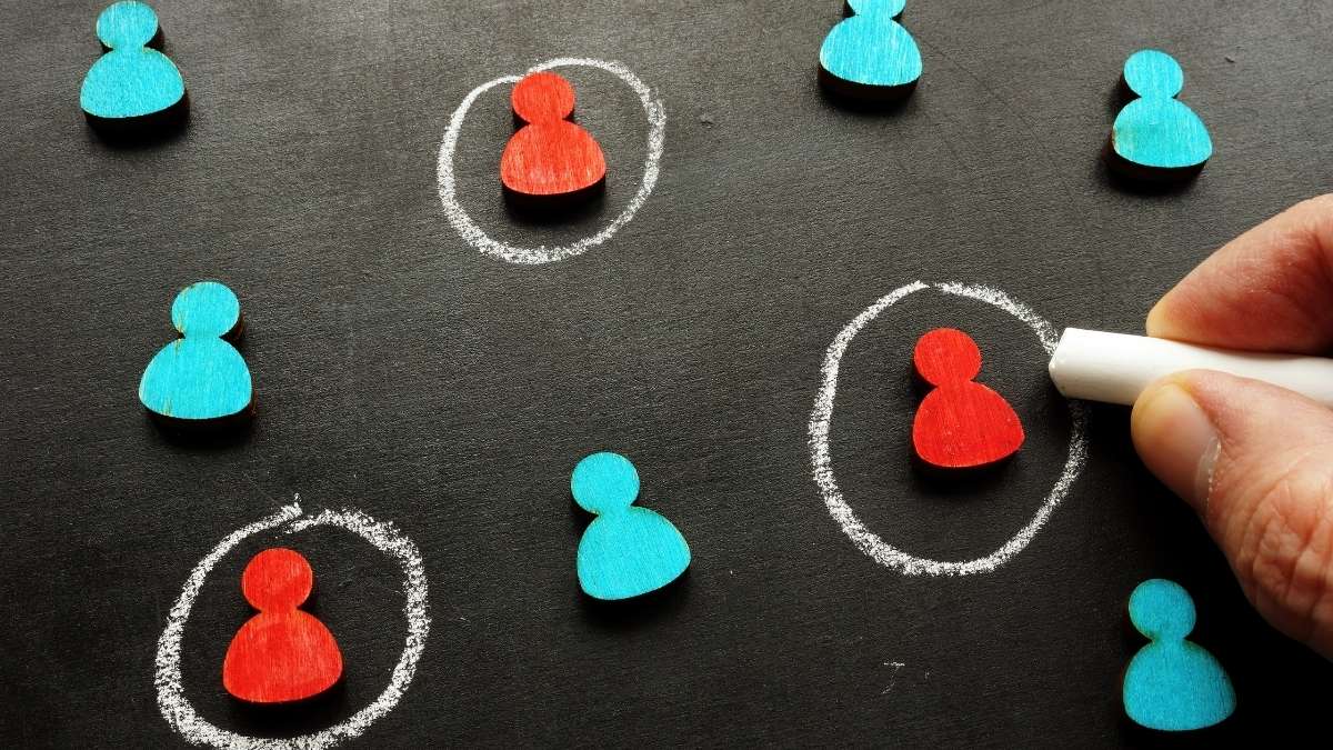Hand drawing chalk circles around red figures on a blackboard, illustrating audience targeting
