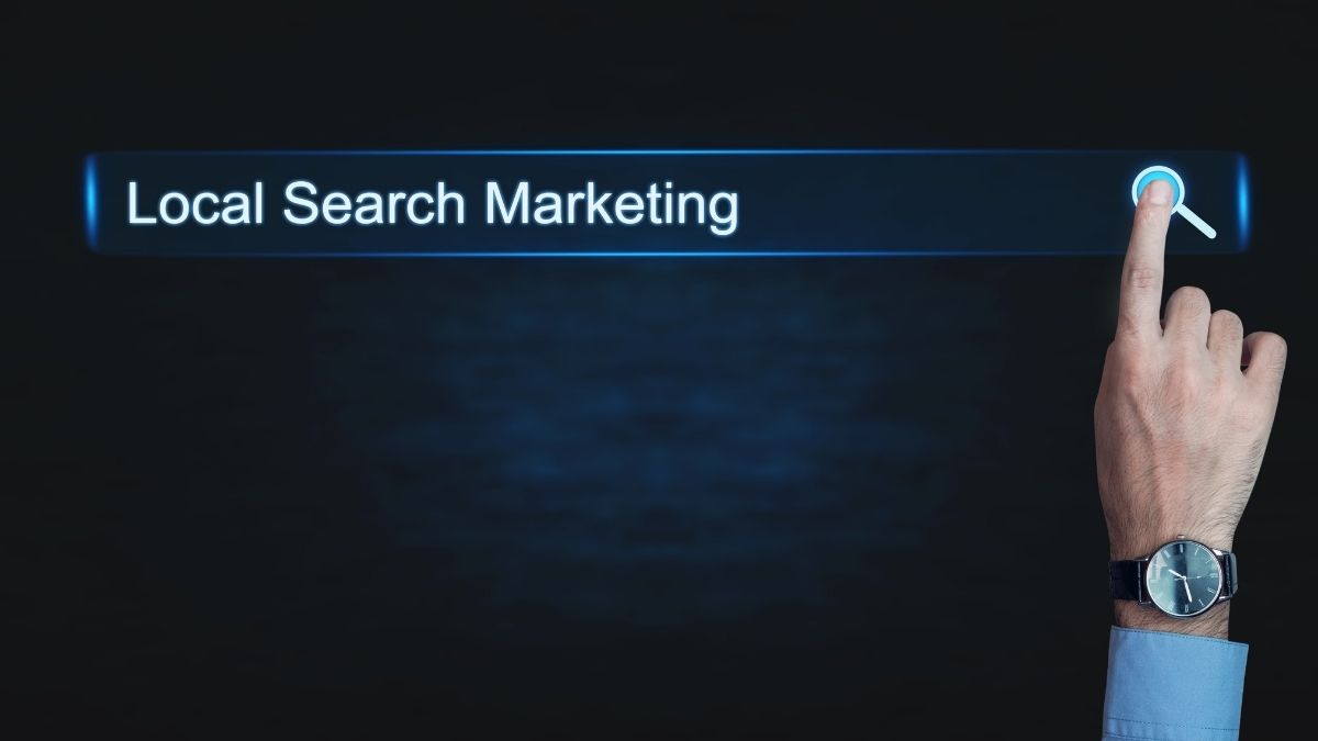 Hand pointing to a glowing Local Search Marketing search bar on a dark background